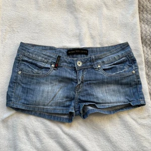 Muskeeter Denim jeans shorts  - Snygga blå jeansshorts från Muskeeter Denim med coola stjärndetaljer på fickorna med låg midja. Tvärs över midjan är de 40cm