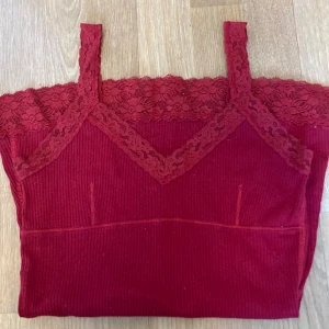 Röd ribbad linne med spetsdetaljer - Snygg röd ribbad linne med spetsdetaljer vid halsringning och nederkant. Perfekt för en somrig look. Linnet har en tight passform och ärmlös design med smala axelband❤️😍🥰