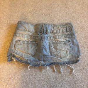 Jeanskjol från Bershka - Säljer en cool jeanskjol från Bershka i ljusblå denim. Kjolen har en kort längd med slitna kanter och två knappar framtill. Perfekt för en avslappnad stil. Även lågmidjad. Säljer pågrund av flytt och för mycket kläder☺️☺️ lite skrynklig då jag inte har strukit den