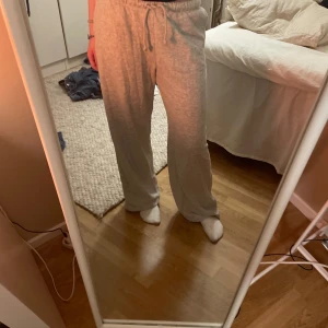 Grå mjukisbyxor med snörning - Säljer ett par bekväma grå mjukisbyxor med snörning i midjan. Perfekta för en avslappnad dag hemma eller på språng. Byxorna har en loose passform och är tillverkade i mjukt material för extra komfort. Har aldrig använt, är jättemysiga!