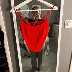 Röd linnetopp från BikBok - Snygg röd linnetopp från BikBok med smala axelband. Perfekt för en färgglad look. Toppen är i en härlig röd färg och har en enkel design som passar till mycket.