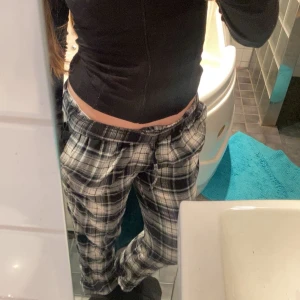 Rutig pyjamas byxa i bomull - Säljer ett par bekväma rutiga byxor i bomull. Byxorna har en elastisk midja och ett avslappnat snitt, perfekt för en chill dag hemma. Färgerna är en mix av svart, vit och grå, vilket ger en klassisk look. L i stories men de är korta i längd!🫶🔥