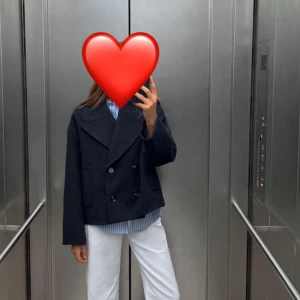 Kappa - Snygg svart kappa med dubbelknäppning och bred krage. Perfekt för en stilren look. Passar bra över en skjorta eller tröja.