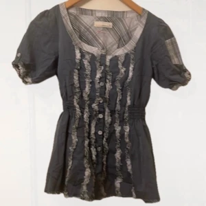 Gråblå babydoll liknande blus med volangdetaljer - fin topp med resår runt midjan, den passar mig bekvämt men för en tajtare passform skulle det passa m/l med 🩷