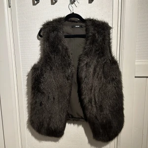 Svart pälsväst från Bik Bok - Snygg och trendig svart pälsväst från Bik Bok. Perfekt för att lägga till en touch av stil till din outfit. Västen är mjuk och fluffig, vilket gör den både bekväm och chic.