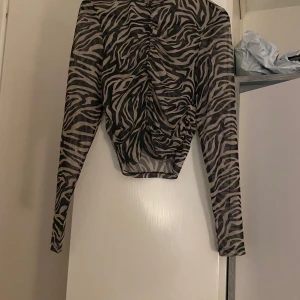 Två mönstrade topp från Amisu - Snygg zebramönstrad och leopardmönstrad topp från Amisu i svart och beige & svart och grön. Toppen har långa ärmar och en åtsittande passform. 