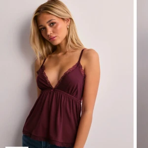 Vinröd linne med spetsdetaljer - Snygg vinröd linne med spetsdetaljer och smala axelband. Toppen har en djup v-ringning och en lös passform som ger en avslappnad look. 