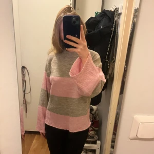 Randig stickad tröja - Säljer en mysig randig tröja från H&M Divided i rosa och grått. Tröjan har långa vida ärmar och en bekväm passform. Perfekt för en avslappnad stil. Hör av dig vid intresse! 💖