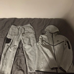 Nike tech  - Säljer en grå Nike tech dress. Storlek M på tröjan Storlek L på byxorna. Nike loggan på byxorna tappade färgen i tvätten som synd på bild 2. Säljer endast båda samtidigt. 