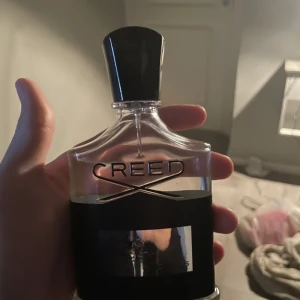 Creed Aventus Parfym - Säljer en exklusiv flaska Creed Aventus parfym, 100 ml. Flaskan har en elegant design med svart och silver detaljer. Perfekt för den som vill ha en lyxig doftupplevelse. Skriv innan köp