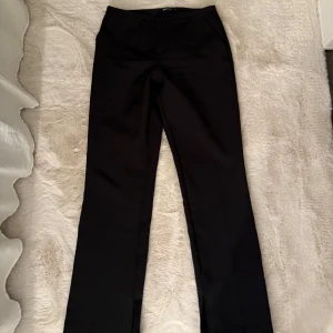 Svarta kostymbyxor - Säljer dessa fina svarta mid waist kostymbyxor med en slit nertill. Passar bra i längd på mig (167-168cm)  Använda några gånger