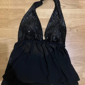 Halterneck topp - Snygg svart halterneck topp med glittriga paljetter på överdelen. Perfekt för en utekväll.