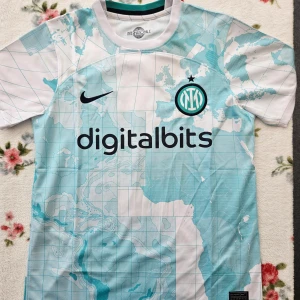 Inter Milan fotbollströja - Snygg Inter Milan fotbollströja från Nike med ett unikt kartmönster i ljusblått och vitt. Tröjan har korta ärmar och klubbens emblem på bröstet. Perfekt för fans som vill sticka ut på läktaren eller planen.