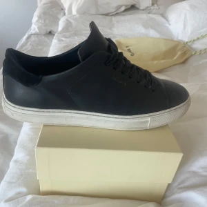 Svarta sneakers från Axel Arigato - Snygga svarta sneakers från Axel Arigato med stilren design och snörning. Skorna har en vit sula som ger en fräsch kontrast. Perfekta för en minimalistisk look. Pris kan absolut diskuteras👍