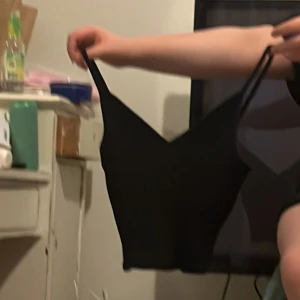 Svart ärmlös linnetopp - Säljer en stilren svart ärmlös linnetopp med smala axelband. Perfekt för varma dagar eller som ett lager under en jacka. Enkel och mångsidig design.