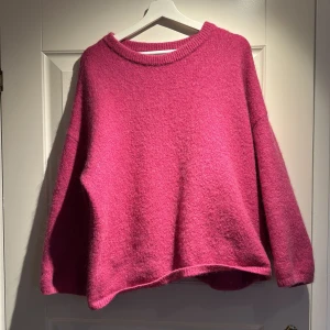 Rosa stickad tröja - Säljer en mysig rosa stickad tröja med lång ärm. Perfekt för kyliga dagar och ger en härlig färgklick till garderoben. Tröjan har en avslappnad passform och rund halsringning. Ordinare pris 999kr. Aldrig använd