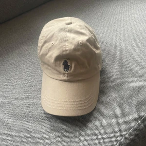 Polo Ralph Lauren keps  - Säljer en beige Ralph lauren keps eftersom den tyvärr aldrig kommer till användning. Köpte de för några år sedan och har knappt använts. Skriv om ni har frågor!