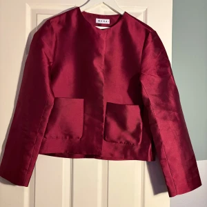 Vinröd jacka från Wera - Snygg vinröd jacka från Wera med en stilren design. Jackan har långa ärmar och två stora fickor framtill. Perfekt för att ge en färgklick till din outfit. 🧥✨