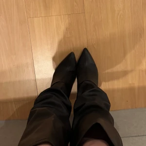 Svarta stövlar med spetsig tå - Snygga svarta stövlar med spetsig tå och hög skaft. Perfekta för en stilren look. De har en elegant design som passar till många olika outfits.
