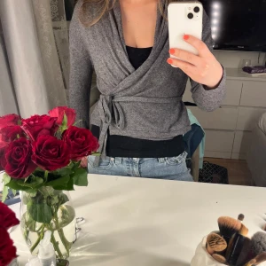 Grå omlottkofta - Säljer en grå omlottkofta med snörning. Superskön och mysig!! Hör av er vid frågor😊