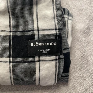 Rutig byxa från Björn Borg - Säljer ett par svartvita rutiga byxor från Björn Borg. Byxorna har en elastisk midja för extra komfort och är perfekta för en avslappnad stil. De är tillverkade i ett mjukt material som känns skönt mot huden. Nypris 500