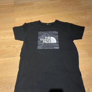 Svart t-shirt från The North Face - Säljer en svart t-shirt från The North Face med ett stort logotryck i vitt på bröstet. T-shirten har en klassisk passform och är kortärmad, perfekt för vardagsbruk.