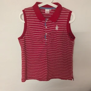 Vintage retro Röd- och vitrandig ärmlös polotopp från Northbrook - Snygg röd- och vitrandig ärmlös polotopp från Northbrook Sports. Toppen har en klassisk krage och knappar framtill. Postar inom tre dagar efter köpet 