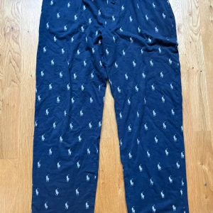 Polo Ralph Lauren pyjamasbyxor - Polo Ralph Lauren pyjamasbyxa i mörkt blått med vitt mönster. Byxan har en resår i midjan och en dragsko för att justera passformen. Bomullstrikå. Herrstorlek small. Djur- o rökfritt hem.