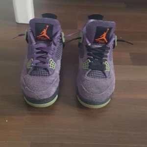 Lila Nike Air Jordans - PRISET KAN DISKUTERAS. Snygga lila Nike Air Jordans med orange detaljer och svart sula. Skorna har en unik design med snörning och är tillverkade i mocka. Perfekta för dig som vill sticka ut med stil. 