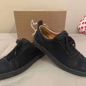 Navy sneakers från Christian Louboutin - Snygga navy sneakers från Christian Louboutin med den ikoniska röda sulan. Skorna har snörning och är tillverkade i mocka. Kvitto finns. 7/10 skick