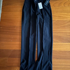 Svarta kostymbyxor från NA-KD - Snygga svarta kostymbyxor från NA-KD med en elegant design. Byxorna har en rak passform och är perfekta för en stilren look. De är tillverkade i ett bekvämt material och har en diskret slits på sidan.
