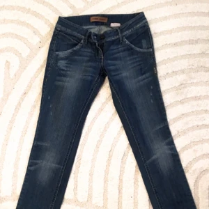 Mörkblå jeansbyxor - Snygga mörkblå jeansbyxor med en klassisk femficksdesign och diskreta slitningar. De har en tight passform och låg midja, perfekt för en trendig look. Byxorna är tillverkade i ett slitstarkt denimtyg.