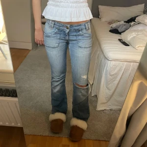 Blå bootcut jeans - Snygga blå bootcut jeans med slitningar på knäet. De har en klassisk femficksdesign och är lågmidjade. Perfekta för en avslappnad stil.  Midja 37cm 🤍🙌🏽🙌🏽