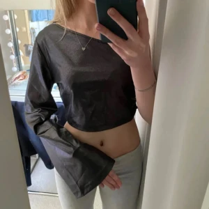 Svart oneshoulder topp - Snygg svart oneshoulder topp med lång ärm och croppad design. Perfekt för en trendig look.