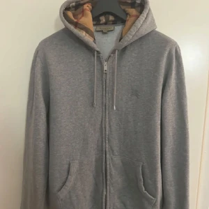 Grå hoodie från Burberry - Jag säljer denna fina tröjan som jag har växt ur den har samt inte använt den så mkt den ser ut o vara ny med inga skador eller liknande skrev för mer information och jag kan tänka mig gå ner i priset vid snabb affär