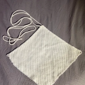 Vit stickad tubtopp - Säljer en vit stickad tubtopp med knytband. Den är öppen men med med knytband på ryggen och lite halterneck. Perfekt för sommardagar och kan stylas på olika sätt. Toppen har en enkel och stilren design. Passar XS/S