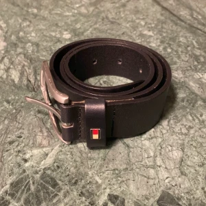 Tommy Hilfiger Läderbälte - Säljer detta klockrena läderbältet från Tommy hilfiger! Har en liten defekt på framsidan (se bild 3), men ingenting som kommer synas! Kontakta gärna om frågor eller pris! Vi syns 🙌!