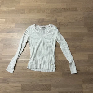 Vit ribbad tröja - Säljer en stilren vit ribbad tröja. Tröjan har en v-ringad hals och långa ärmar, perfekt för lager-på-lager under kyligare dagar. En klassisk baströja som funkar till det mesta.