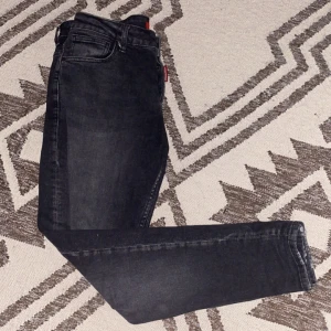 Svarta jeansbyxor - Snygga svarta jeans med en klassisk femficksdesign. De har en rak passform och är perfekta för en stilren look. Byxorna har en knappgylf och är tillverkade i ett slitstarkt material. Är dock ganska breda vid midjan och ganska smala vid fotleden. 