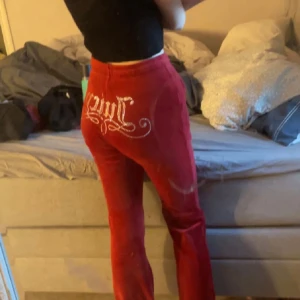 Snygga juicy byxor  - Snygga röda velourbyxor med hög midja och broderad textdetalj på baksidan. Byxorna har en bekväm passform och knytning i midjan för extra stil. Perfekta för en avslappnad look.      Priset kan sänkas vid snabb affär 