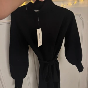 Stickad klänning - Snygg svart klänning i nytt skick.       Storlek Omr size.     Pris 200:-      Den har långa ärmar och ett knytband i midjan för en smickrande passform. Perfekt för höst och vinter, och funkar lika bra till fest som till vardags. Klänningen är i en kort modell och ger en elegant look. Från Missey i Göteborg.