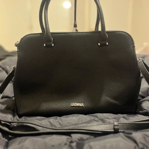 Svart handväska från Catwalk - Snygg svart handväska från Catwalk i mycket bra skick. Väskan har en stilren design med dragkedja och flera fack inuti för smart förvaring. Perfekt för både vardag och fest! 🖤