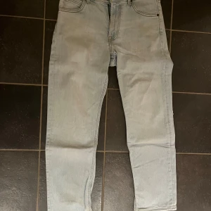 Ljusblå jeans från Lee - Säljer ett par ljusblå jeans från Lee i bra skick. Jeansen har en dragkedja och knapp framtill samt en snygg Lee-logga på baksidan. 