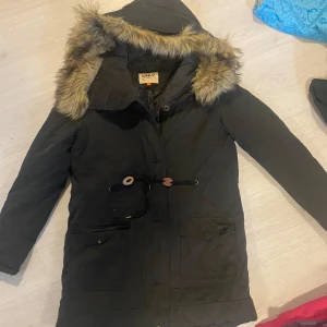 Svart parkajacka från Only - Säljer en svart parkajacka från Only i bra skick. Jackan har en mysig fuskpäls på huvan och knäppning framtill. Perfekt för kalla vinterdagar och höstpromenader. Storleken är dam S och den har långa ärmar. Superbekväm och stilren!
