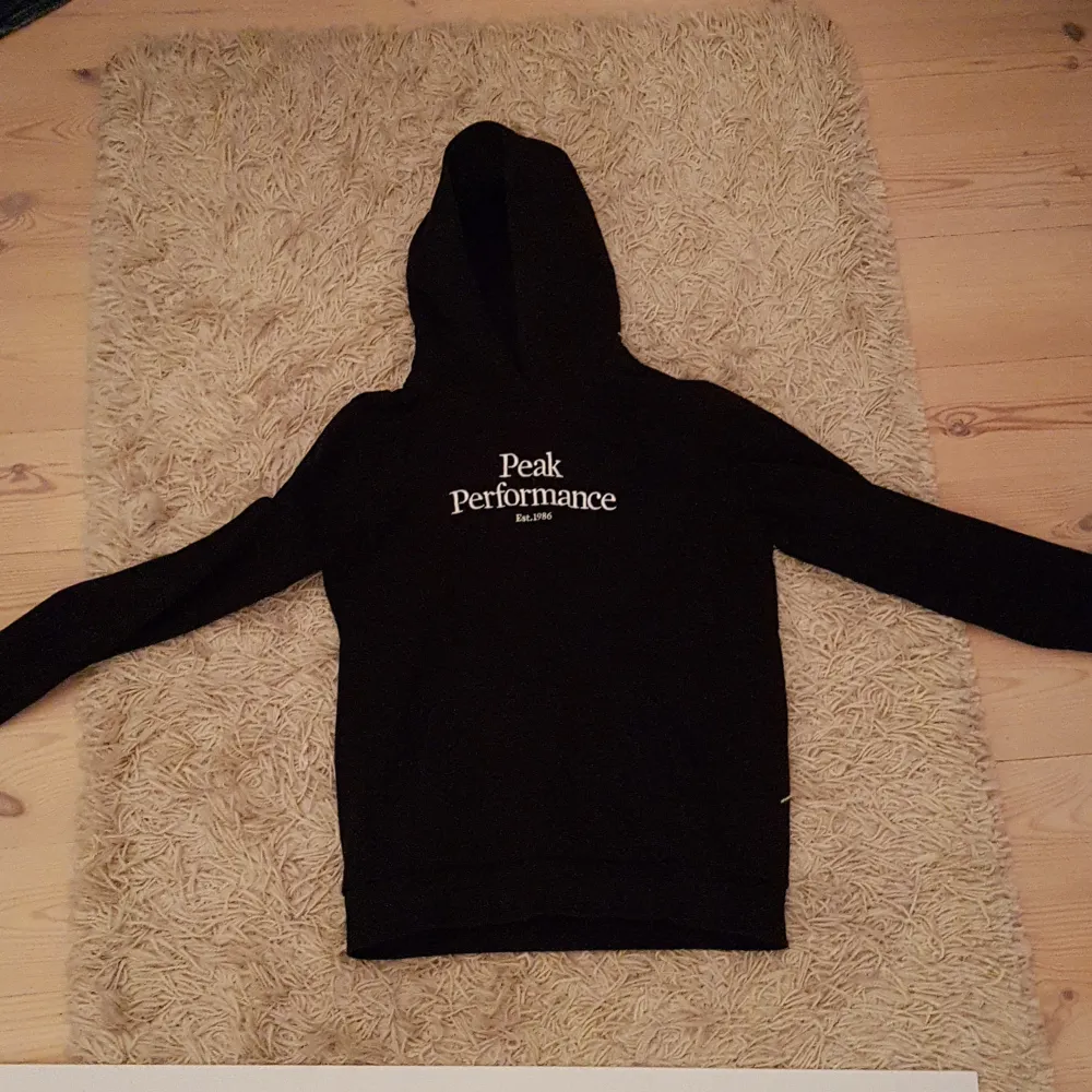 Säljer en svart hoodie från Peak Performance i storlek 160. Den är i ny skick och perfekt för både höst och vinter. Hoodien har en klassisk design med logga på bröstet och är superbekväm. Perfekt för chill dagar eller när du vill ha en stilren look. 🖤. Tröjor & Koftor.