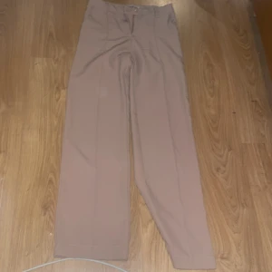 Beige byxor från Madlady - Säljer ett par snygga beige byxor från Madlady i storlek S. De har en klassisk design med hög midja och raka ben, perfekt för både vardag och fest. Byxorna är i mycket bra skick men kommer tyvärr inte till användning då jag var andra byxor som jag hellre använder. 