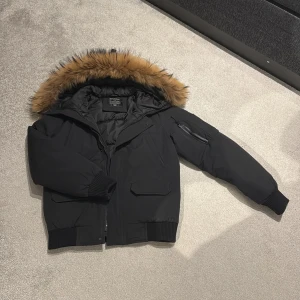 Enos jacka med päls(äkta) - Säljer en snygg svart vinterjacka från Enos med en mysig pälsfodrad huva.(äkta päls) Jackan har långa ärmar och dragkedja framtill. Man kan ta av och sätta på päls huvan. Jackans ny pris är 2800 mitt pris 750. Perfekt för kalla vinterdagar! 🖤