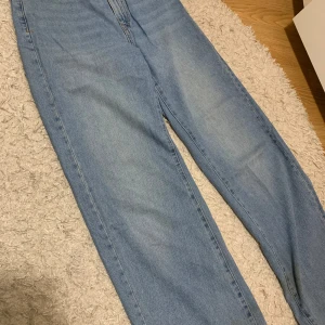 Blå jeans från Lindex - Säljer ett par klassiska blå jeans från Lindex i storlek 36. De har en normal passform och är perfekta för vardagsbruk. Jeansen har en knapp och dragkedja framtill samt fickor både fram och bak. De är i bra skick och redo för en ny ägare!
