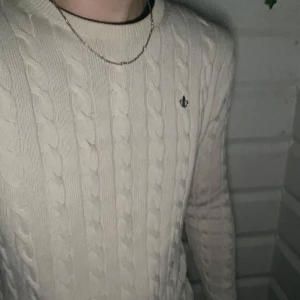 Morris stickad kabel tröja - Säljer en stilren vit stickad tröja med kabelmönster. Perfekt för kyliga dagar och passar både till vardags och lite finare tillfällen. Tröjan har långa ärmar och en diskret logga på bröstet. Supermysig och i bra skick! Storlek S, pris kan diskuteras vid snabb affär 