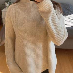 Mysig beige stickad polotröja perfekt för kyliga dagar. Den har en avslappnad passform med långa ärmar och en hög krage som håller dig varm. Perfekt för både höst och vinter! 🧶